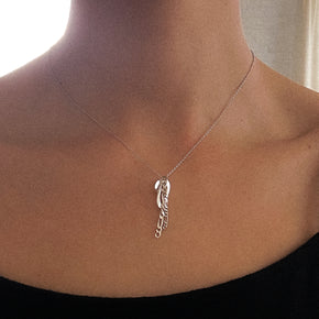 Silver necklace with a pendant on a person's neck against a neutral background