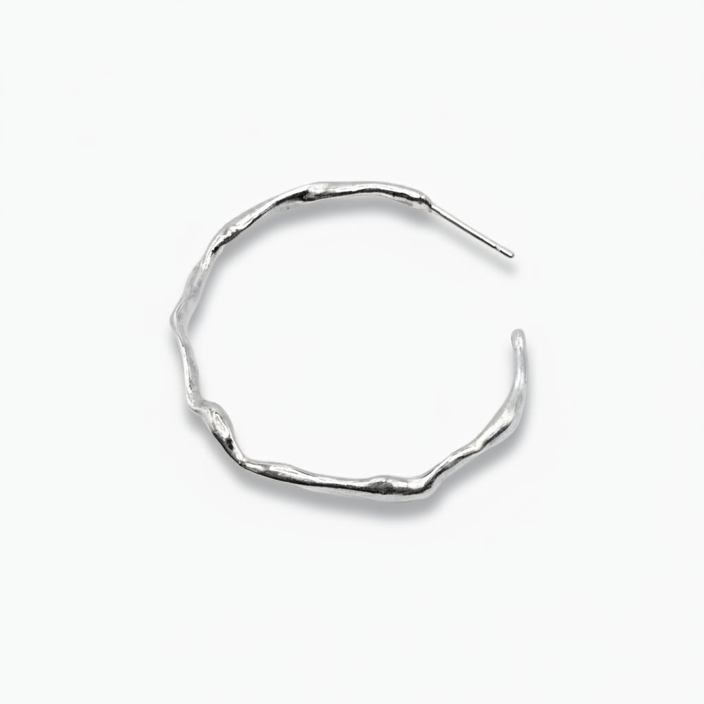 A large hoop earring with a wavy, organic surface, made of sterling silver.