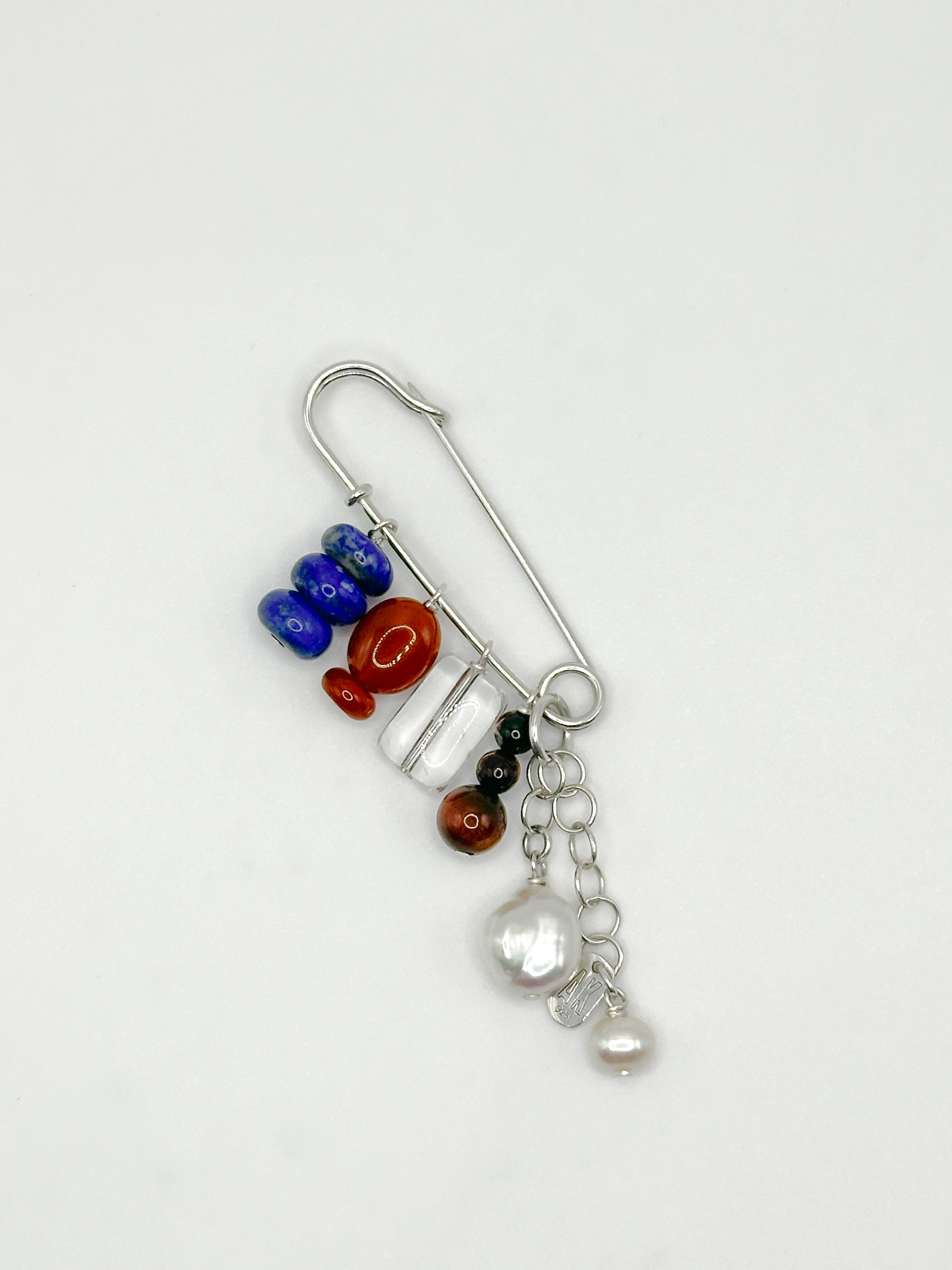 Decorative brooch with colorful semiprecious stones and charms on a white background