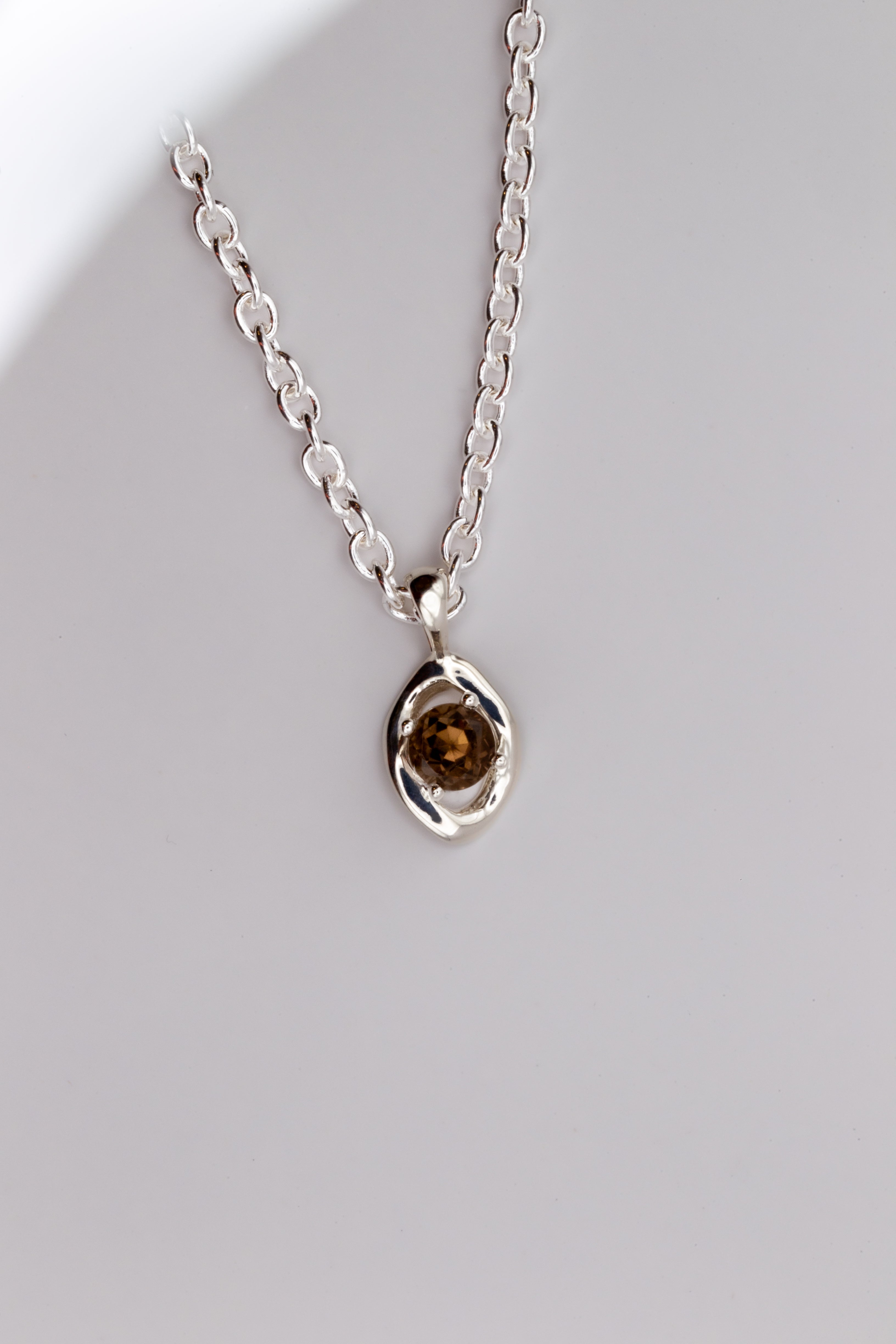 Silver necklace with a pendant on a light gray background