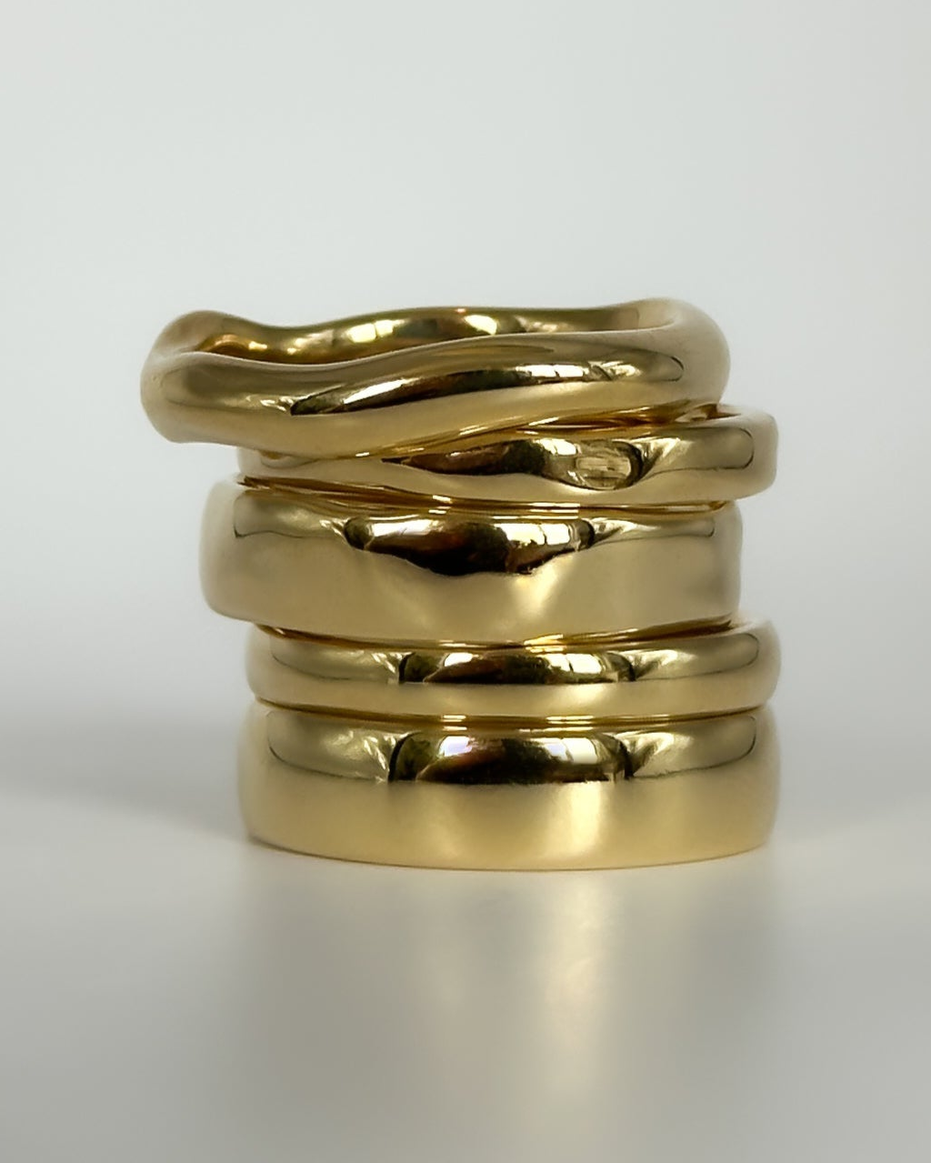 Stack of gold rings on a light gray background