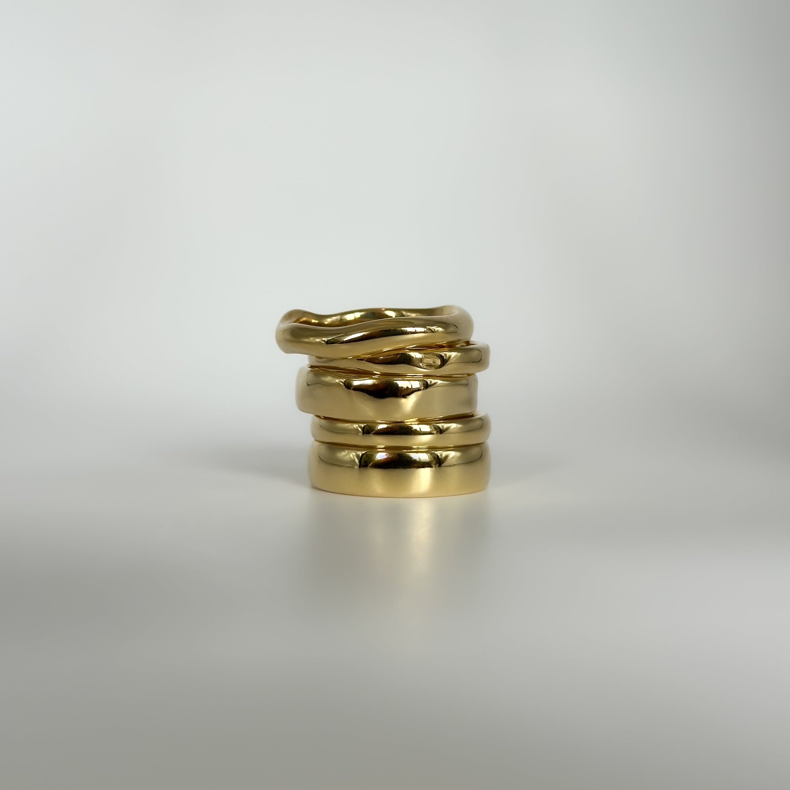 Stack of gold rings on a light gray background