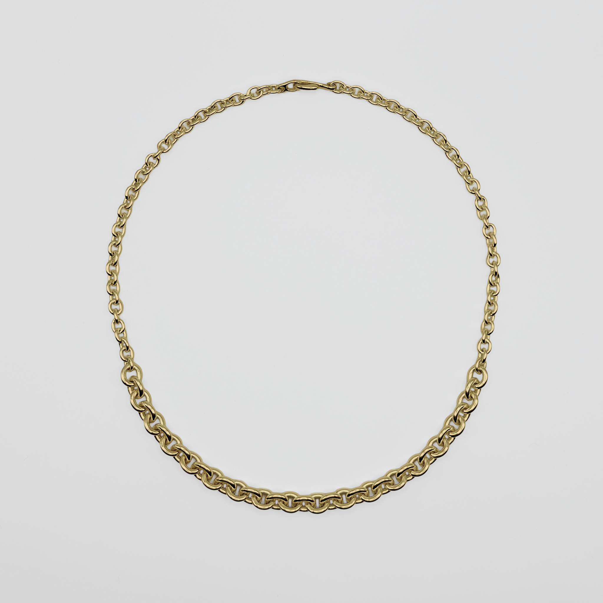 Gold chain necklace on a light gray background