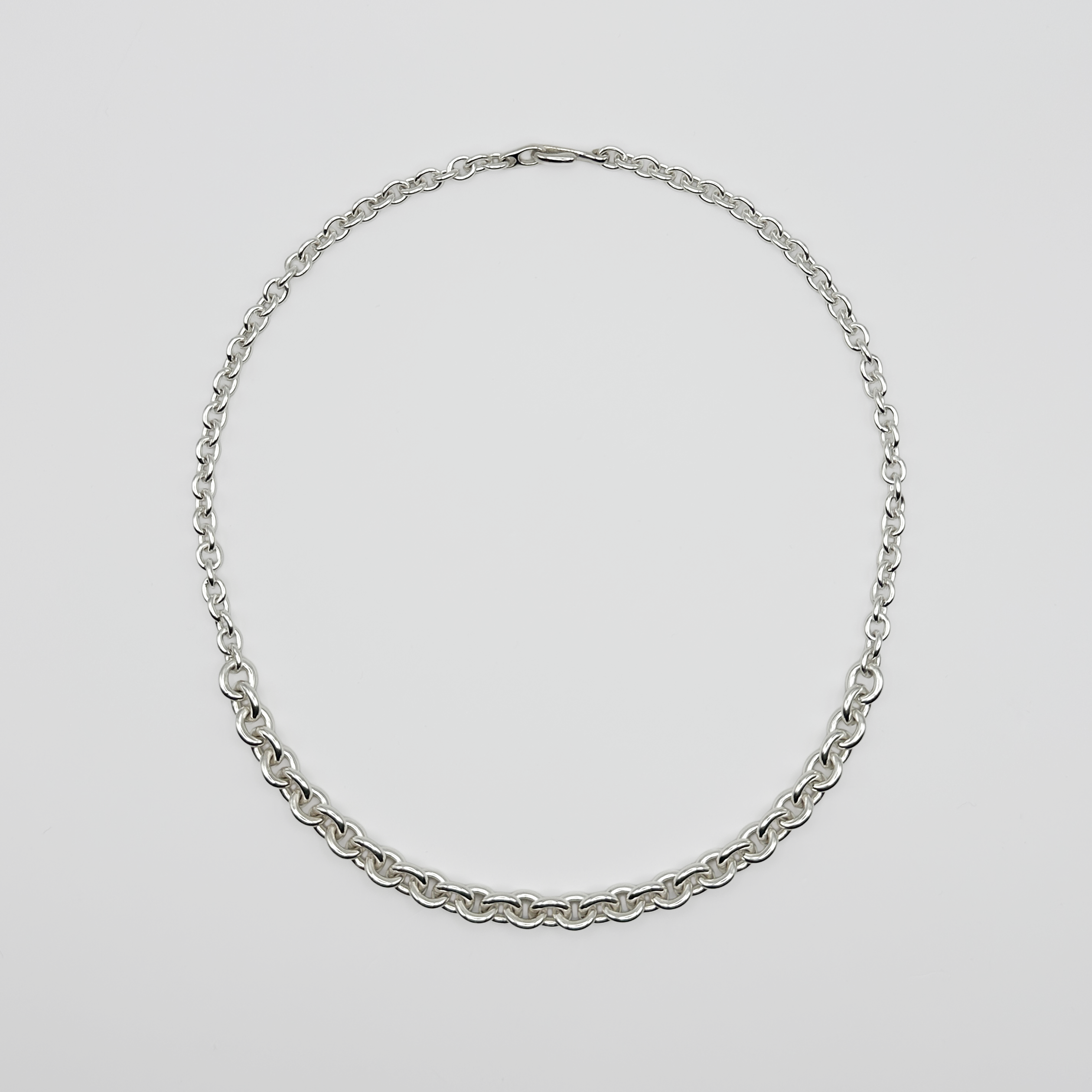 Silver chain necklace on a light gray background
