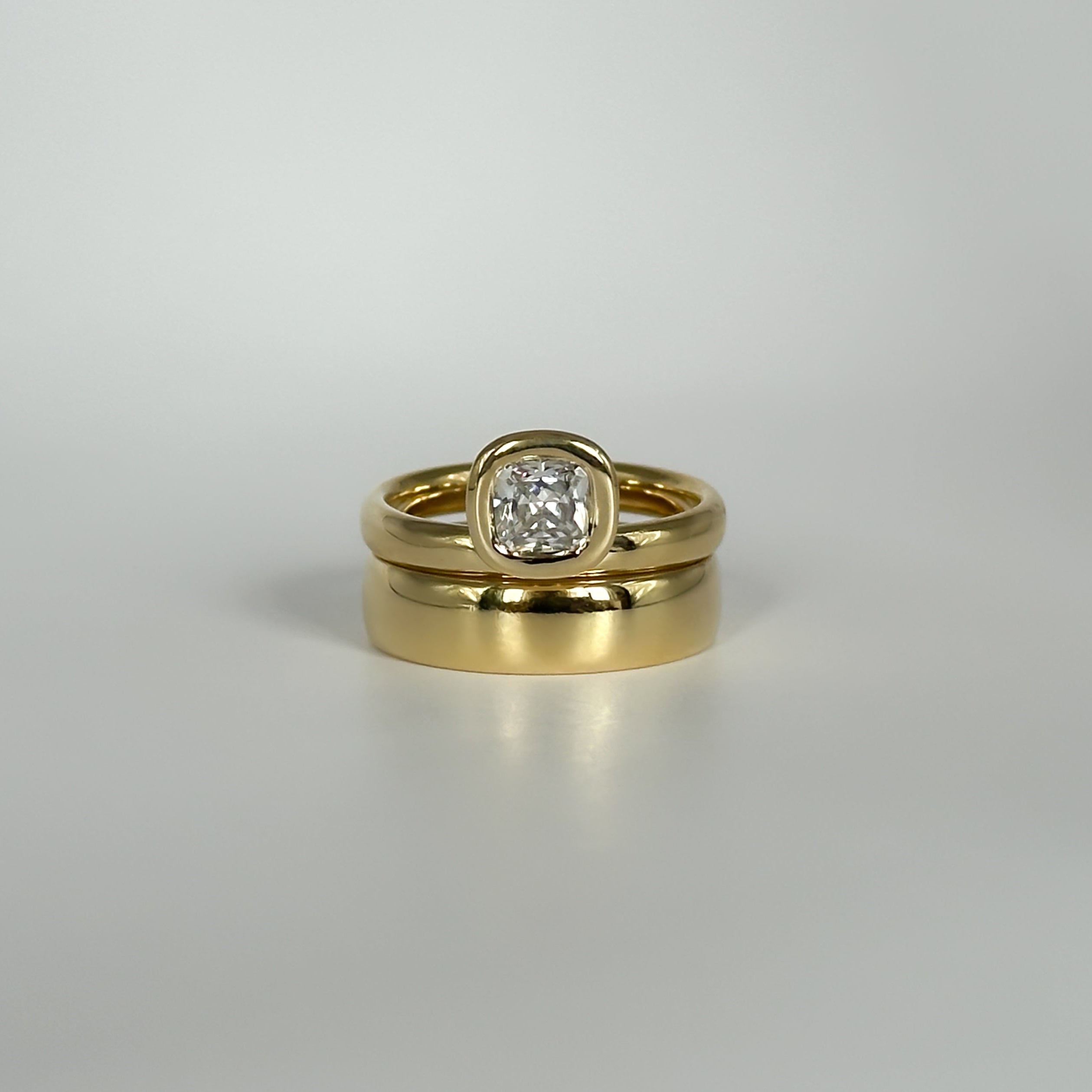Gold rings stacked with a diamond on a light gray background