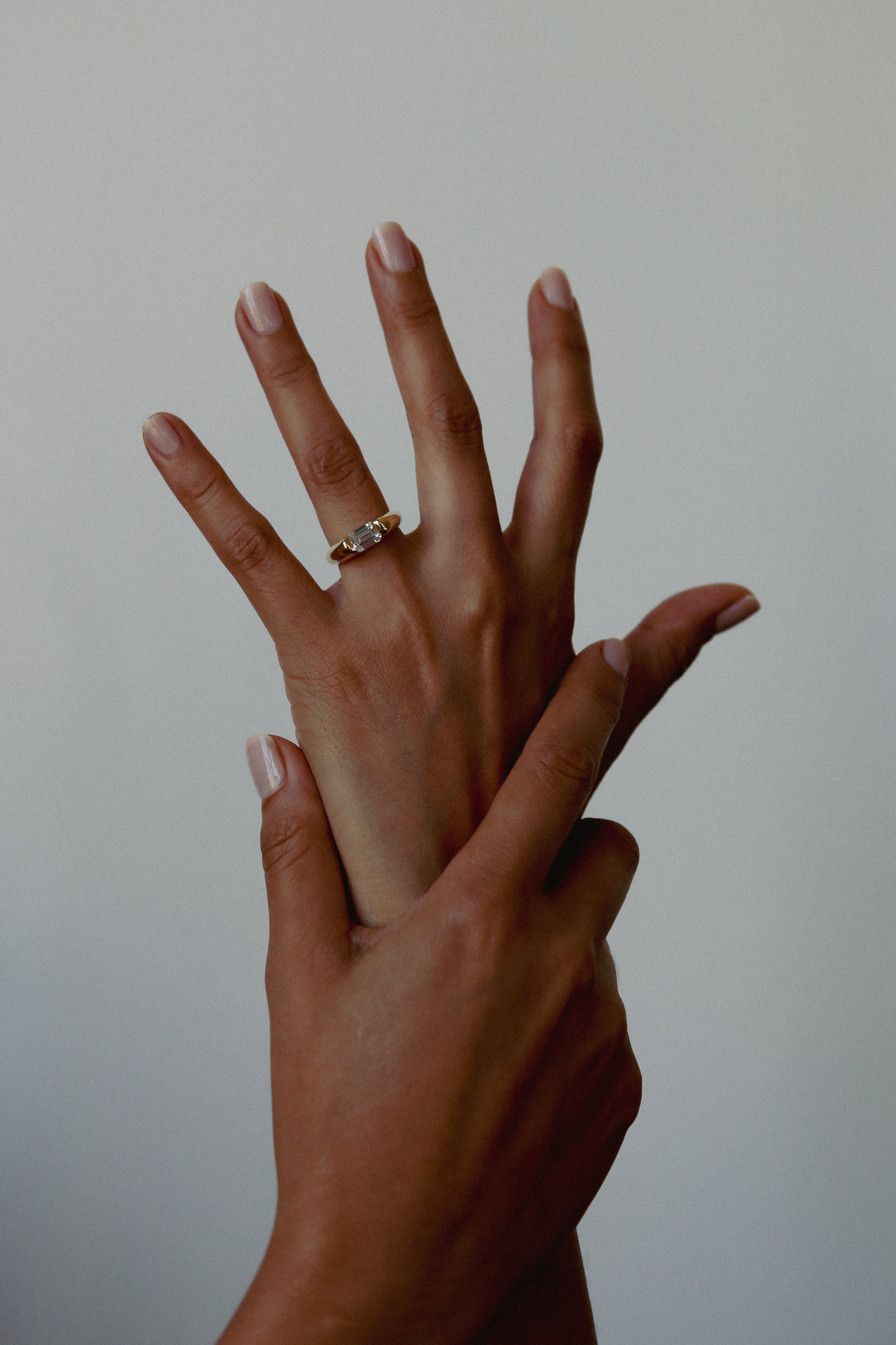 Two hands with a ring on a plain background