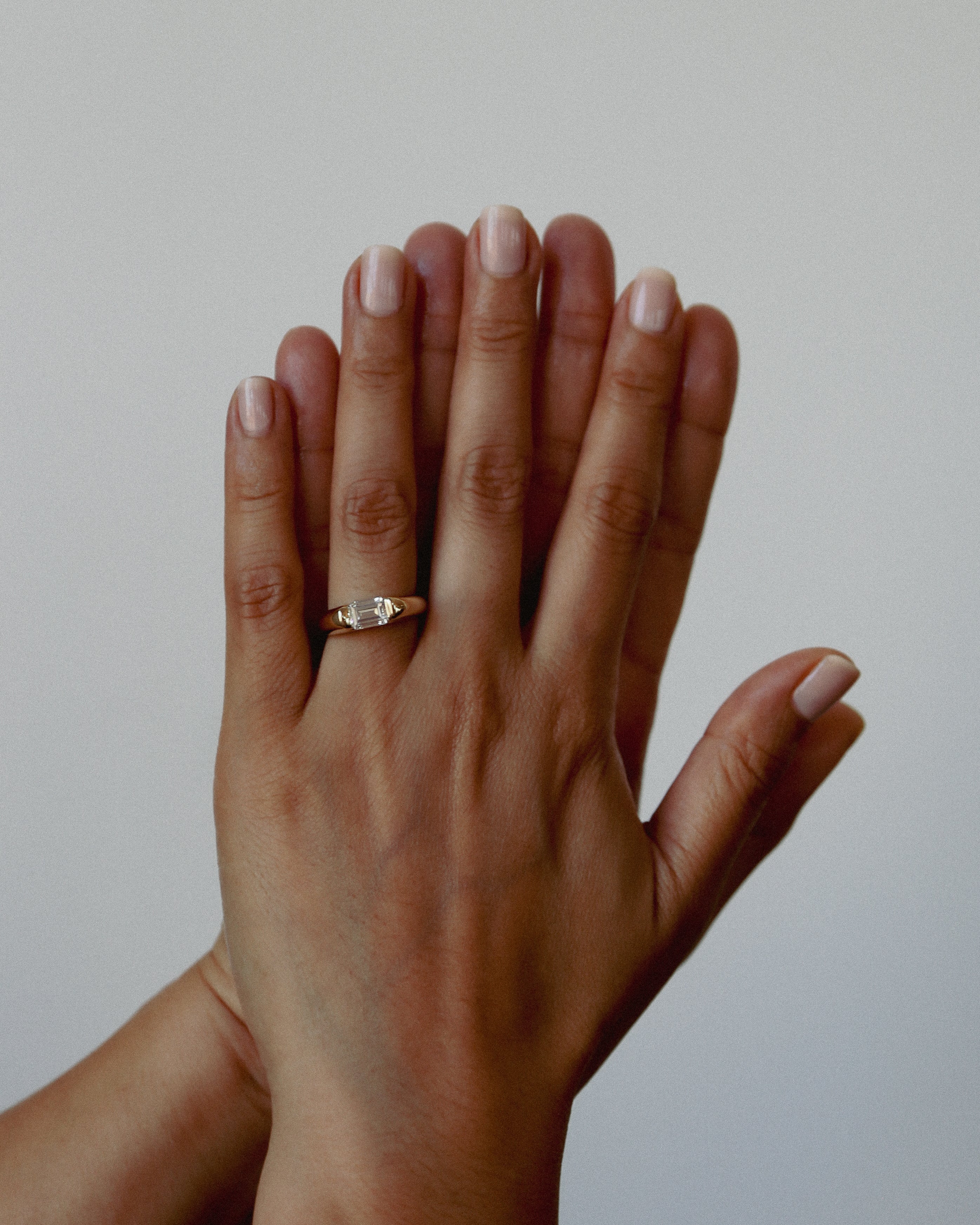 Two hands with a ring on a plain background