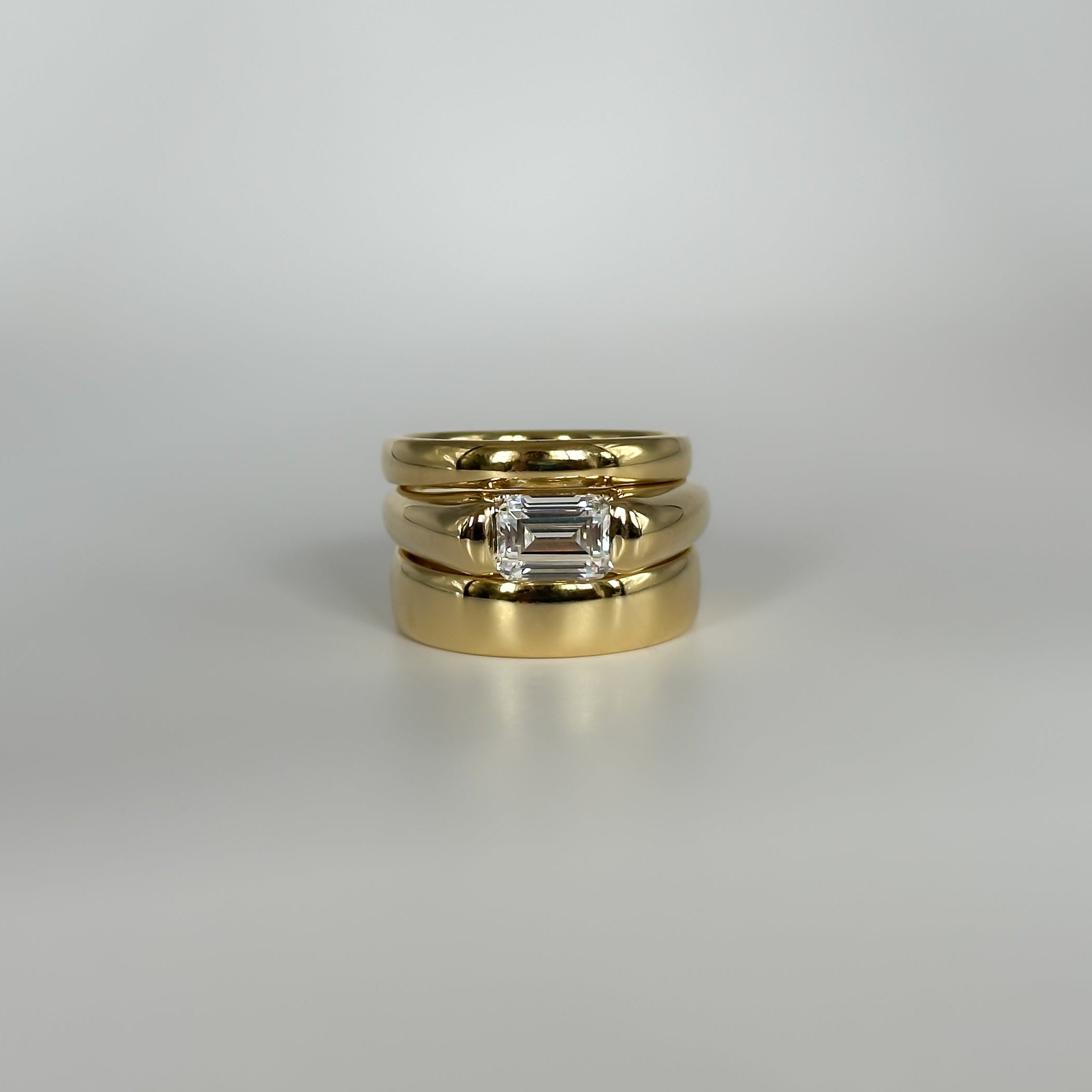 Three gold rings with a diamond on a gray background