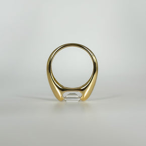 Gold ring with an emerald cut diamond on a light gray background
