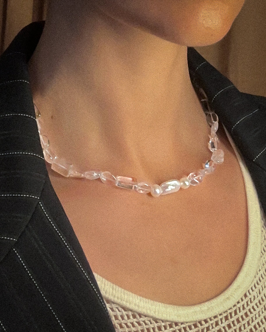 Person wearing a quartz pearl necklace with a neutral background