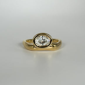 Gold ring with an oval-cut diamond on a light gray background