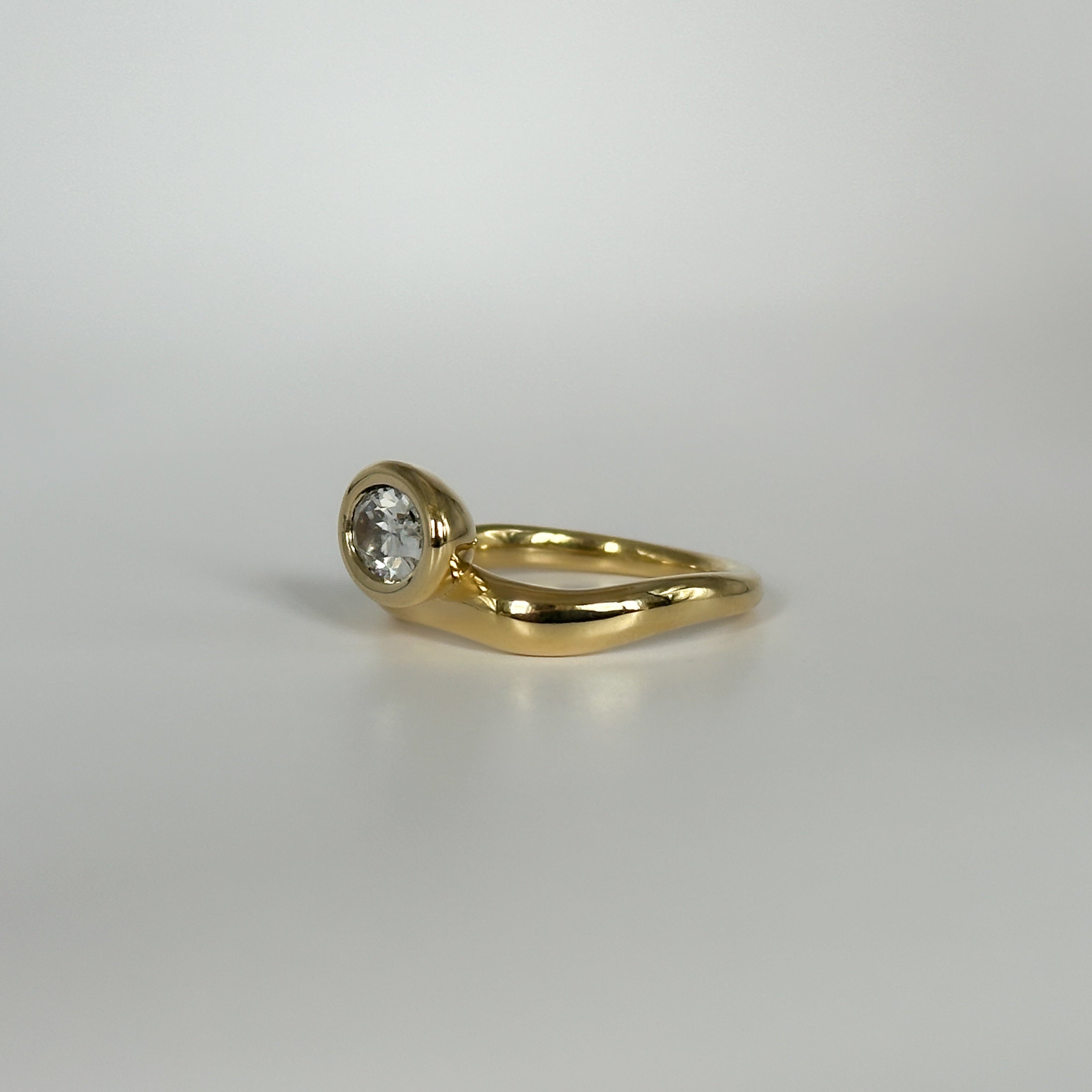 Gold ring with a diamond on a light gray background