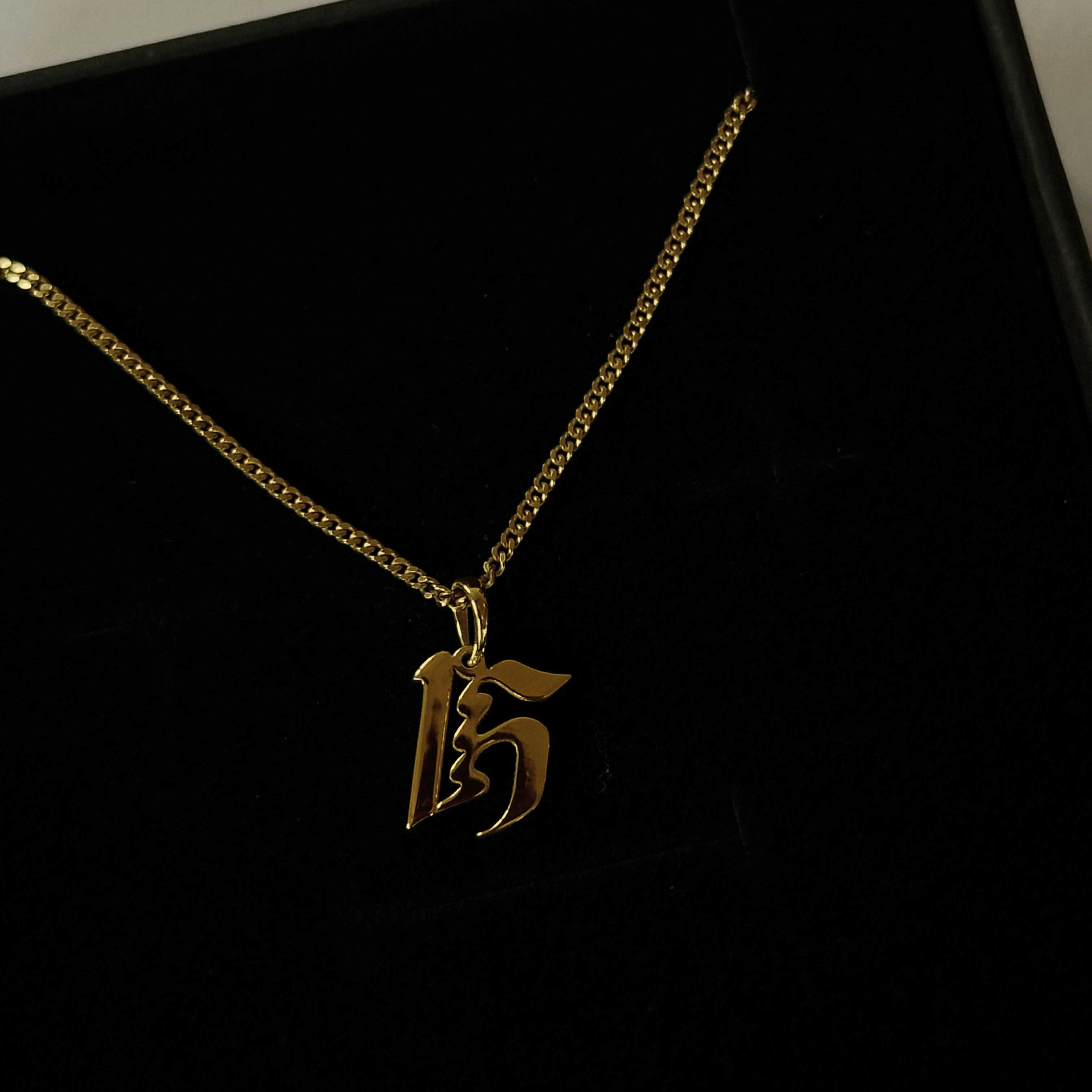 A 14K gold pendant in the shape of the letter 'H' with a chain, against a black background.