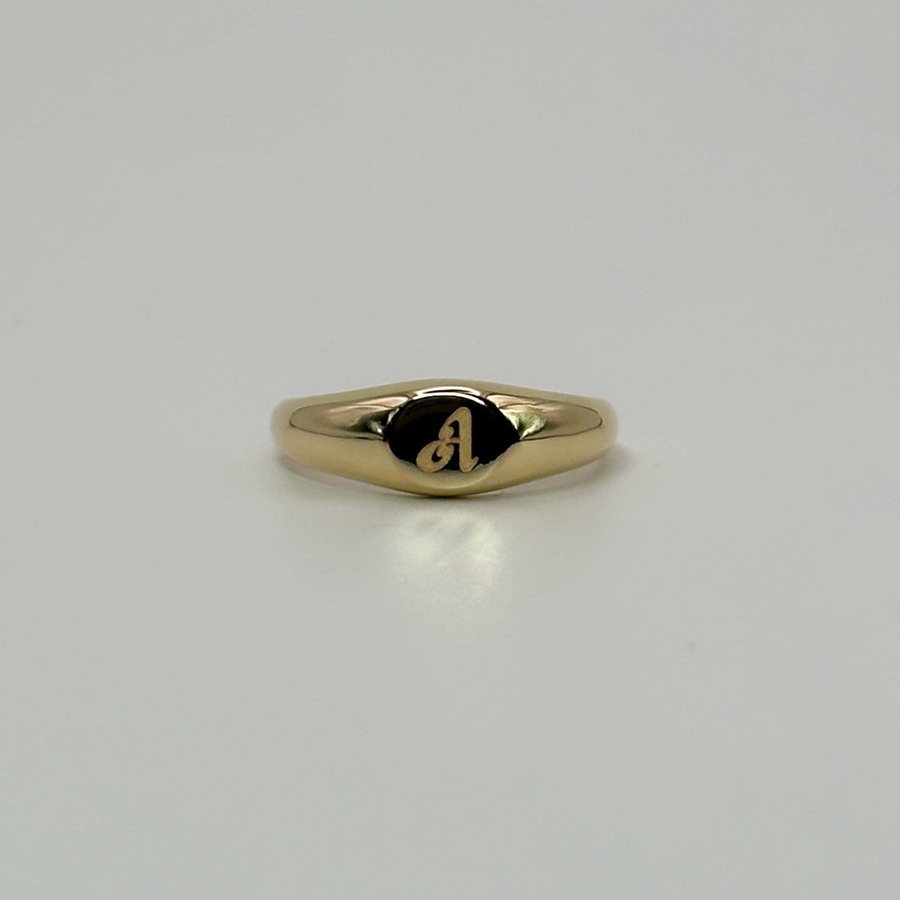 Gold ring with a small engraving on a light gray background