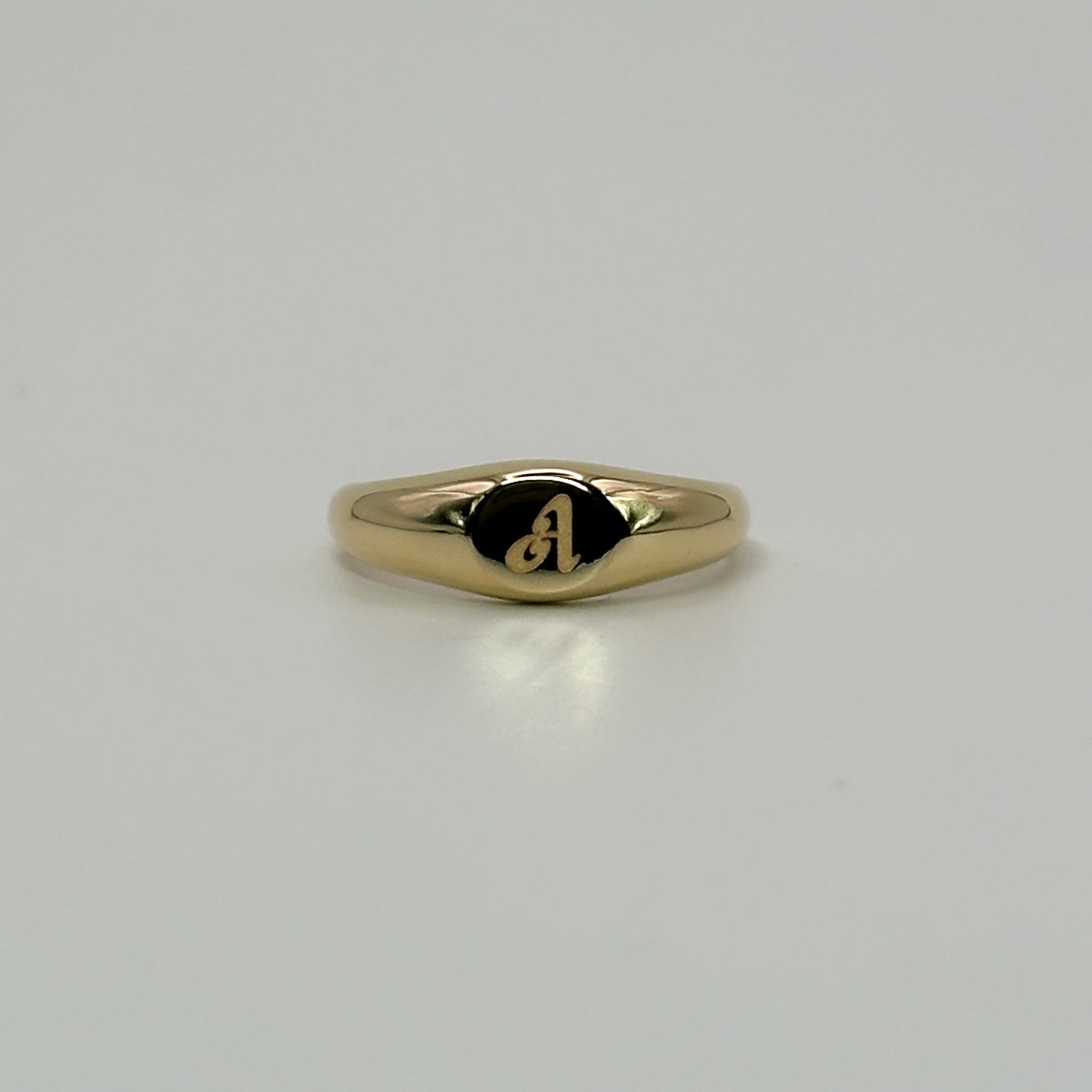 Gold ring with a small engraving on a light gray background