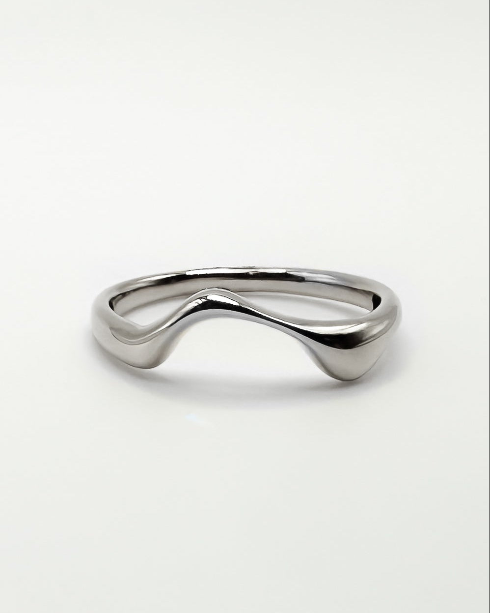 A polished white gold ring with a unique wavy, fluid design, photographed on a seamless light gray background.