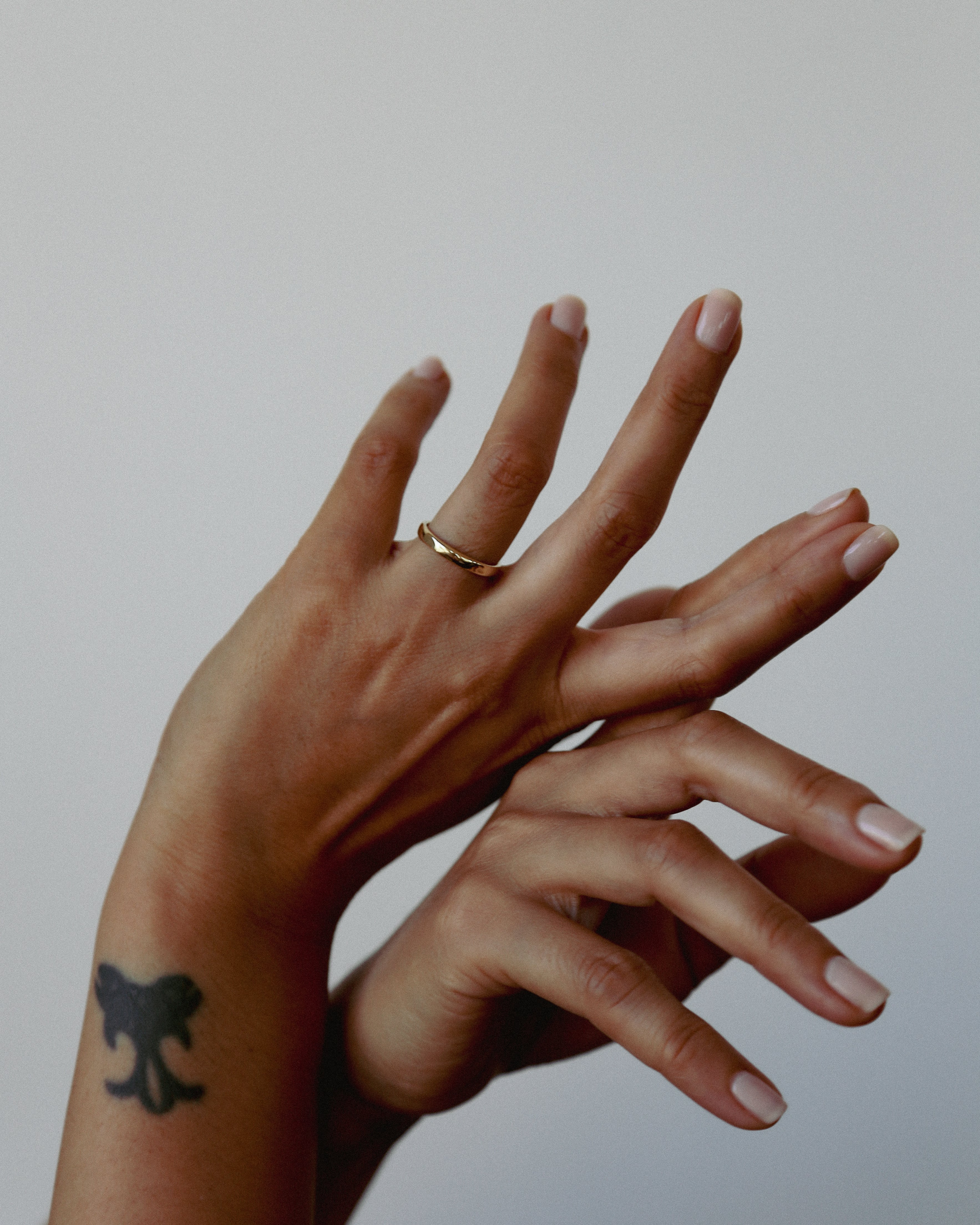 Close-up of a hand with a gold ring on a plain background