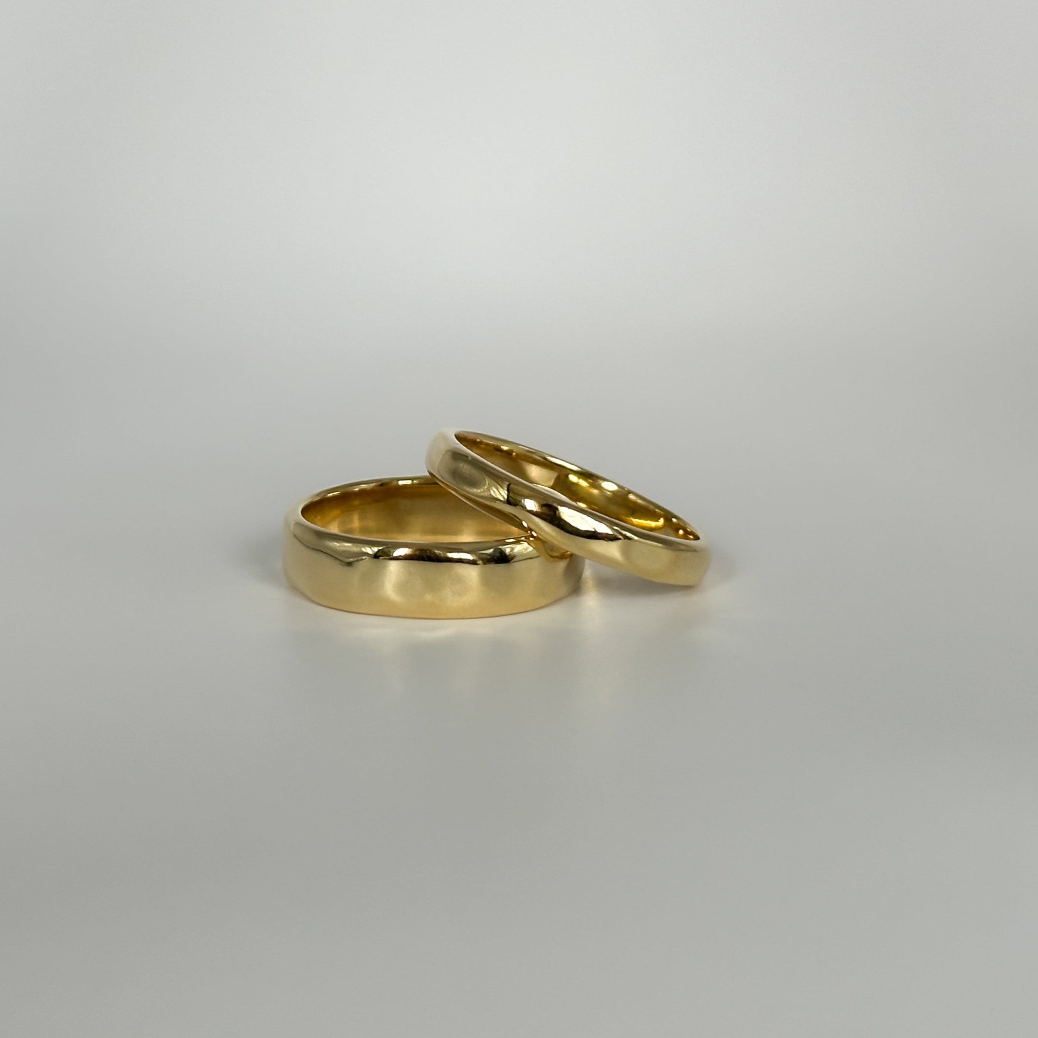Two gold rings on a light gray background