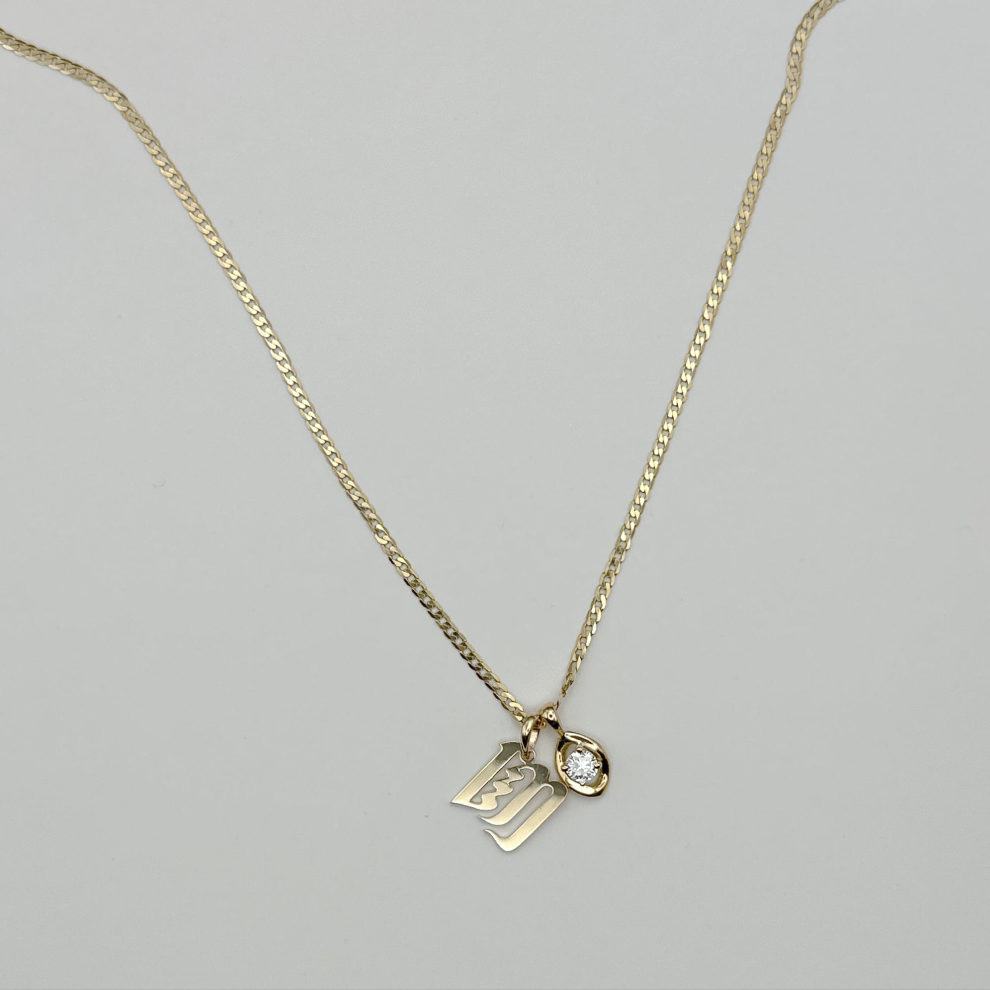 Gold necklace with two pendants on a light gray background